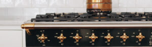 black lacanche range with brass knobs and copper pot